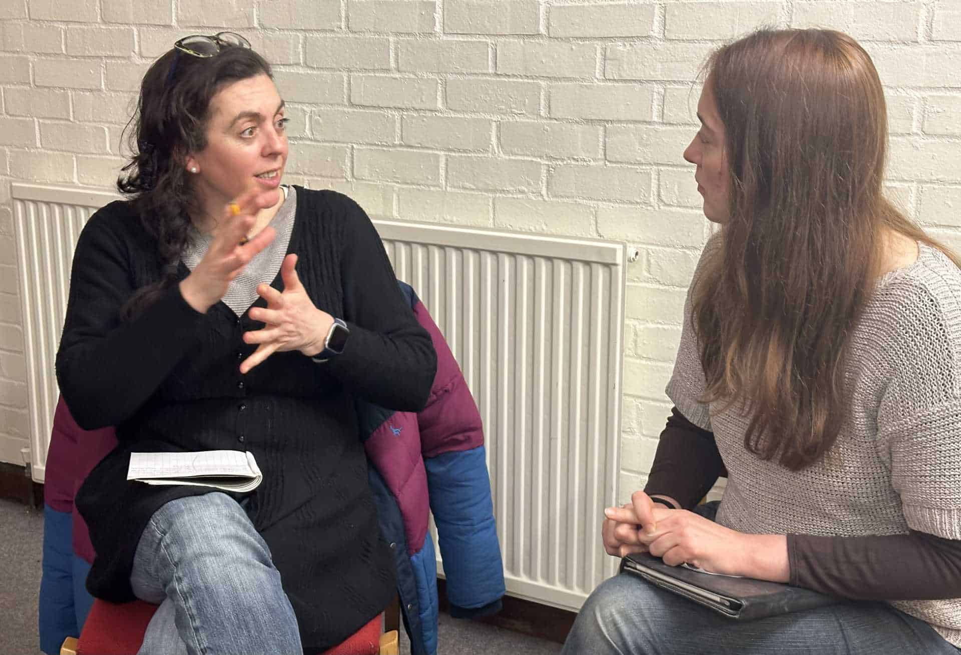 Two women sitting in chairs talking to each other.